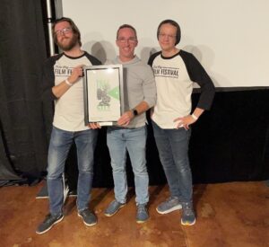 Three men holding a framed picture