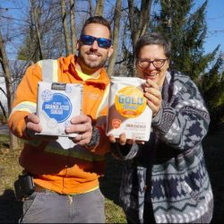 A man holding a bag of sugar and a woman holding a bag of flour.